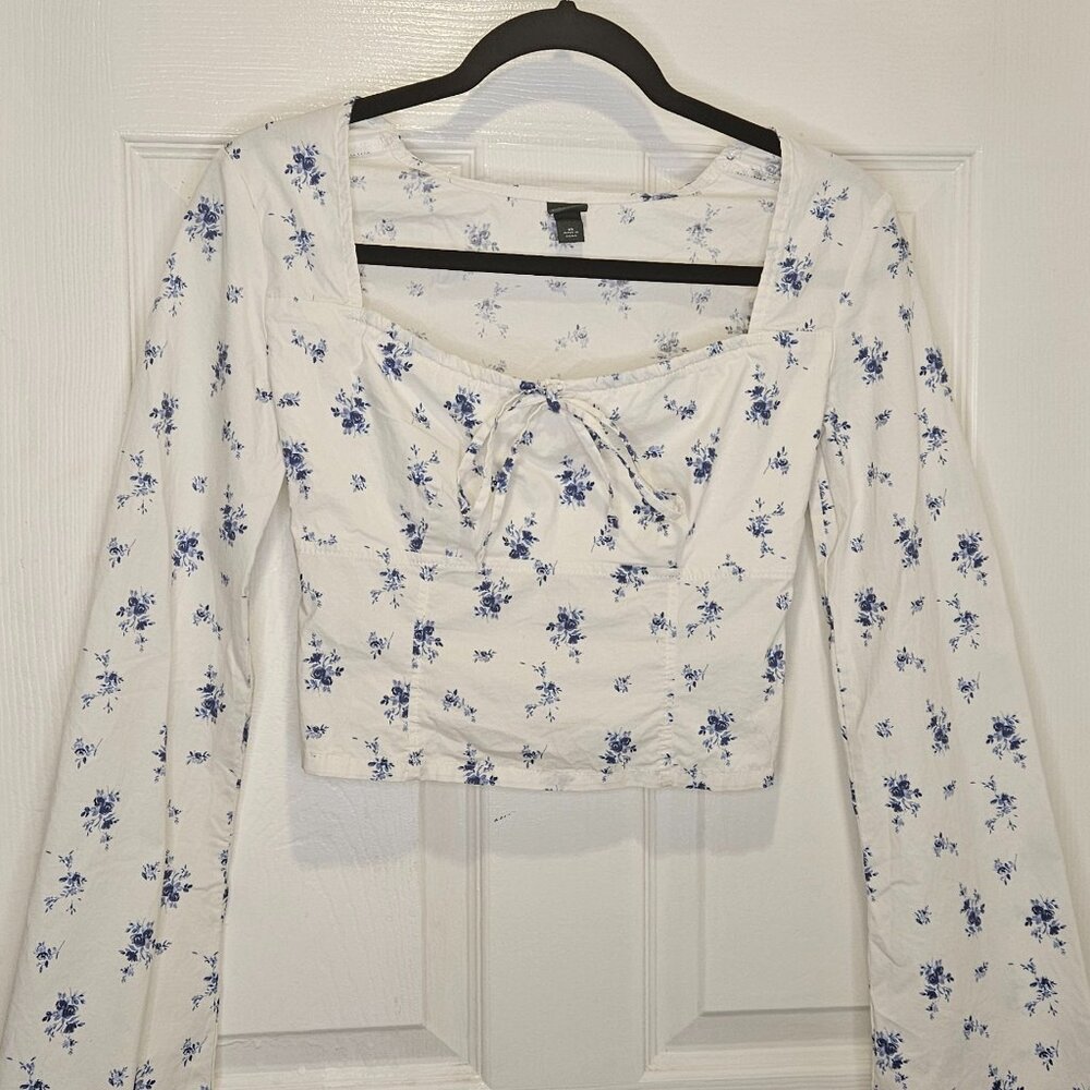 White long sleeve blouse with blue flowers cropped at waist.